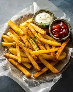 Frozen French Fries in Air Fryer served on parchment with ketchup and mayo dipping sauces.