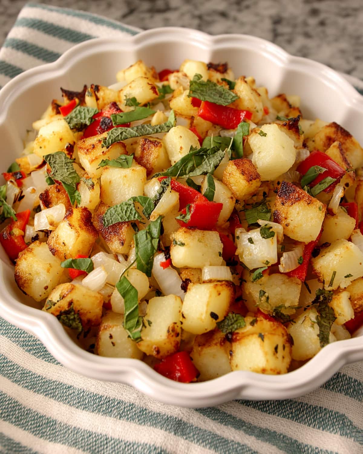 Potatoes O'Brien from Air Fryer in white bowl, with golden diced potatoes, red peppers, onions, and fresh herbs.