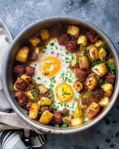Air fryer corned beef hash with crispy potatoes, seasoned beef, sunny-side eggs, and fresh parsley.
