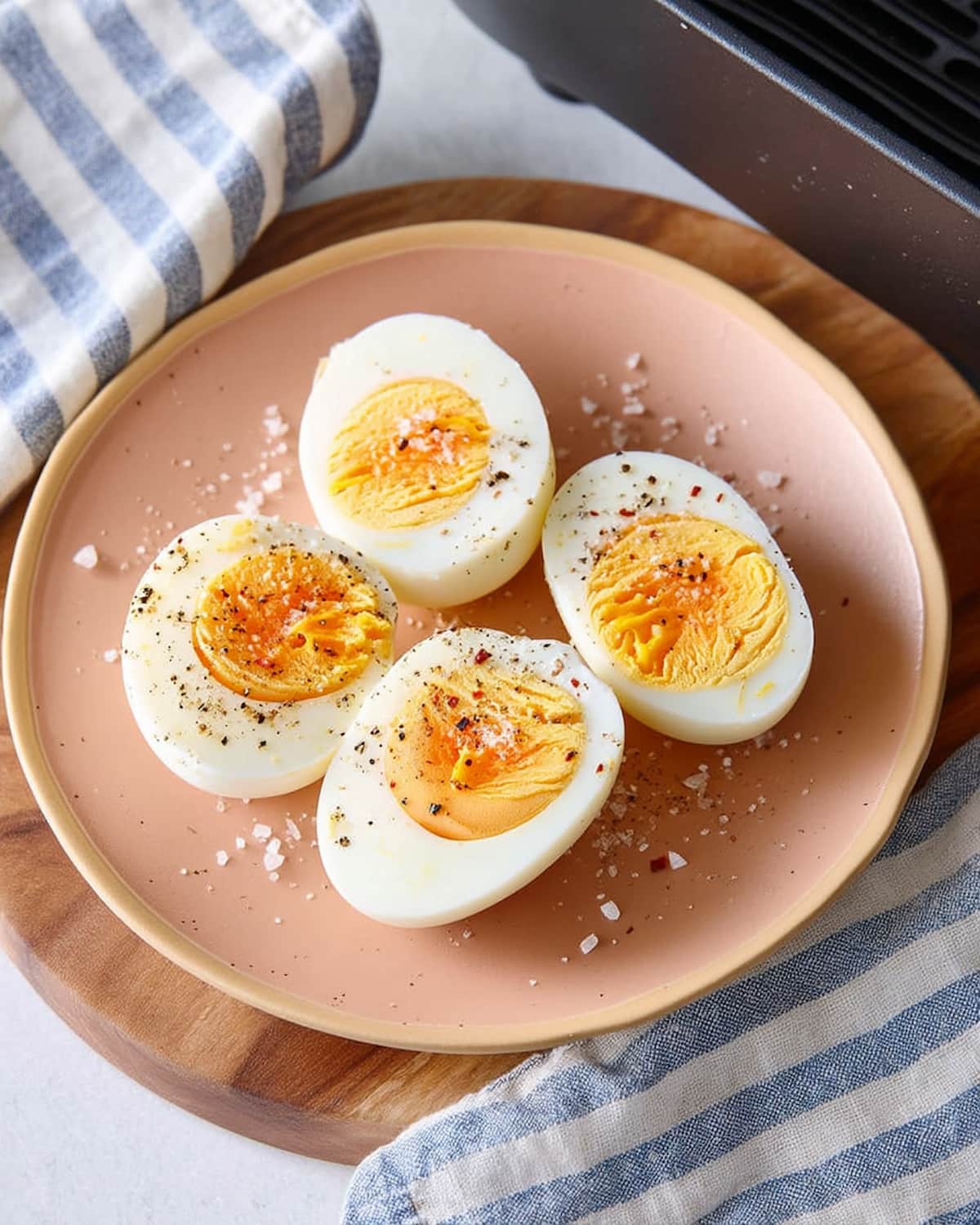 Hard Boiled Eggs in Air Fryer halved on a pink plate, showing creamy golden yolks.