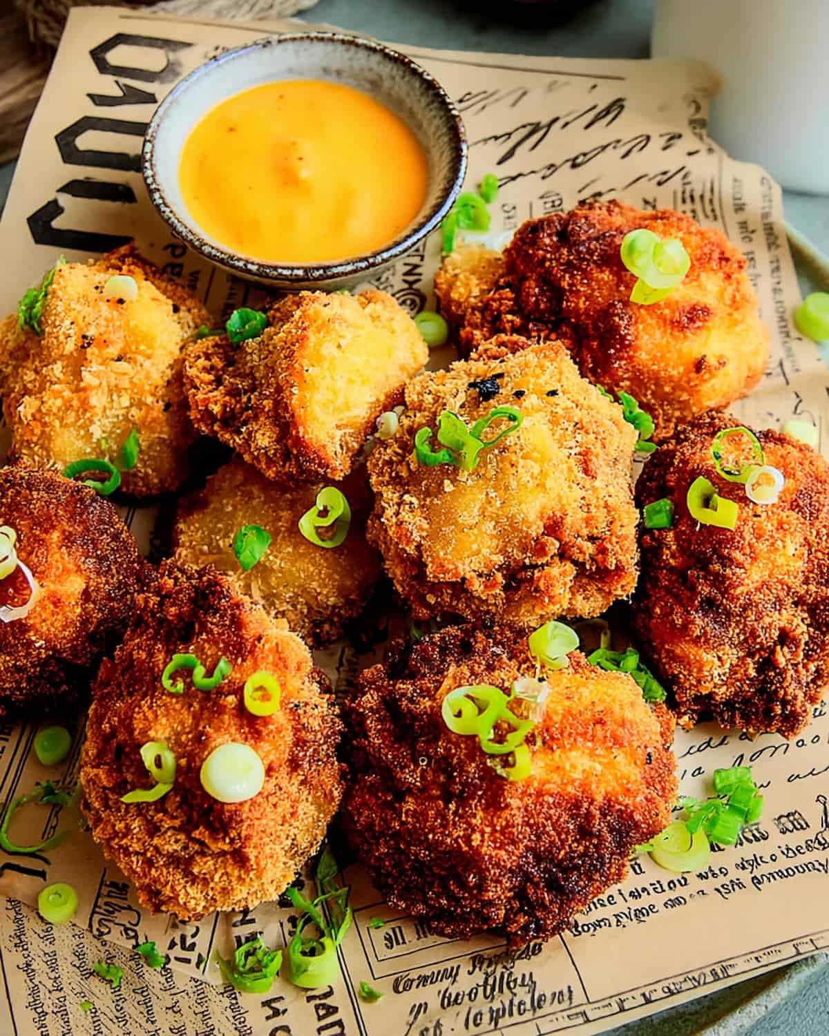 Air Fryer Cauliflower Nuggets, crispy and golden, garnished with green onions and served with a creamy dipping sauce.