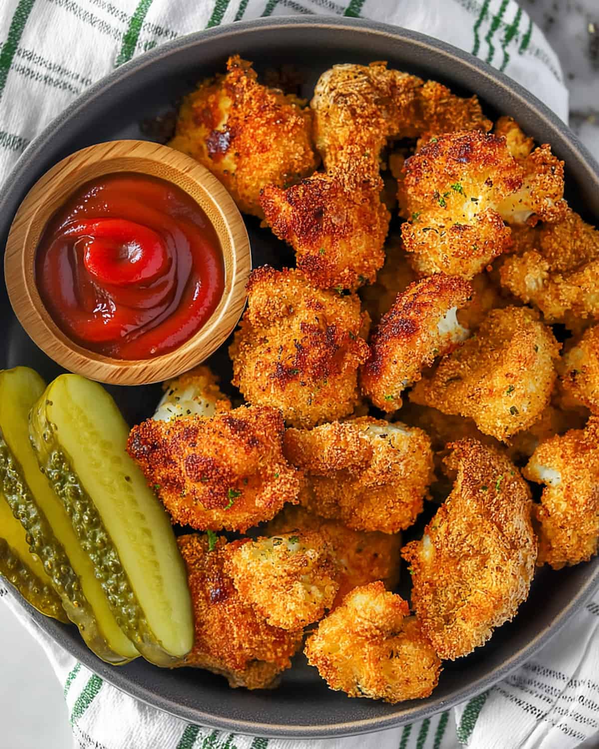 Air fryer gluten-free chicken nuggets with crispy golden coating, ketchup in wooden bowl, and pickle slices.