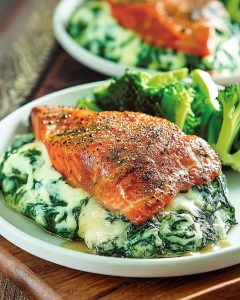 Keto stuffed salmon from air fryer, filled with creamy spinach and cheese mixture, served with steamed broccoli florets.
