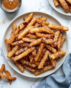 Crispy air fryer apple fries with cinnamon sugar coating in a bowl, golden edges and warm apple centers