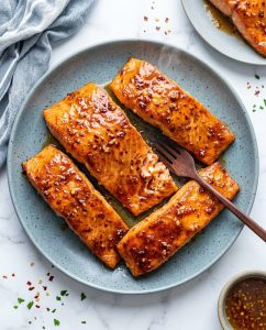 Easy Air Fryer Salmon with honey lemon glaze, glossy caramelized edges and lemon wedges on a plate